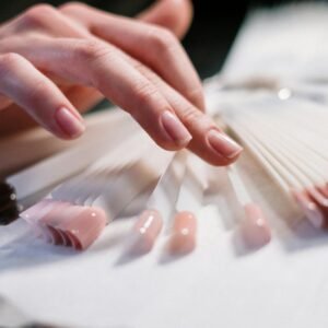 Close-up of a woman's hand selecting nail polish colors in a beauty salon.