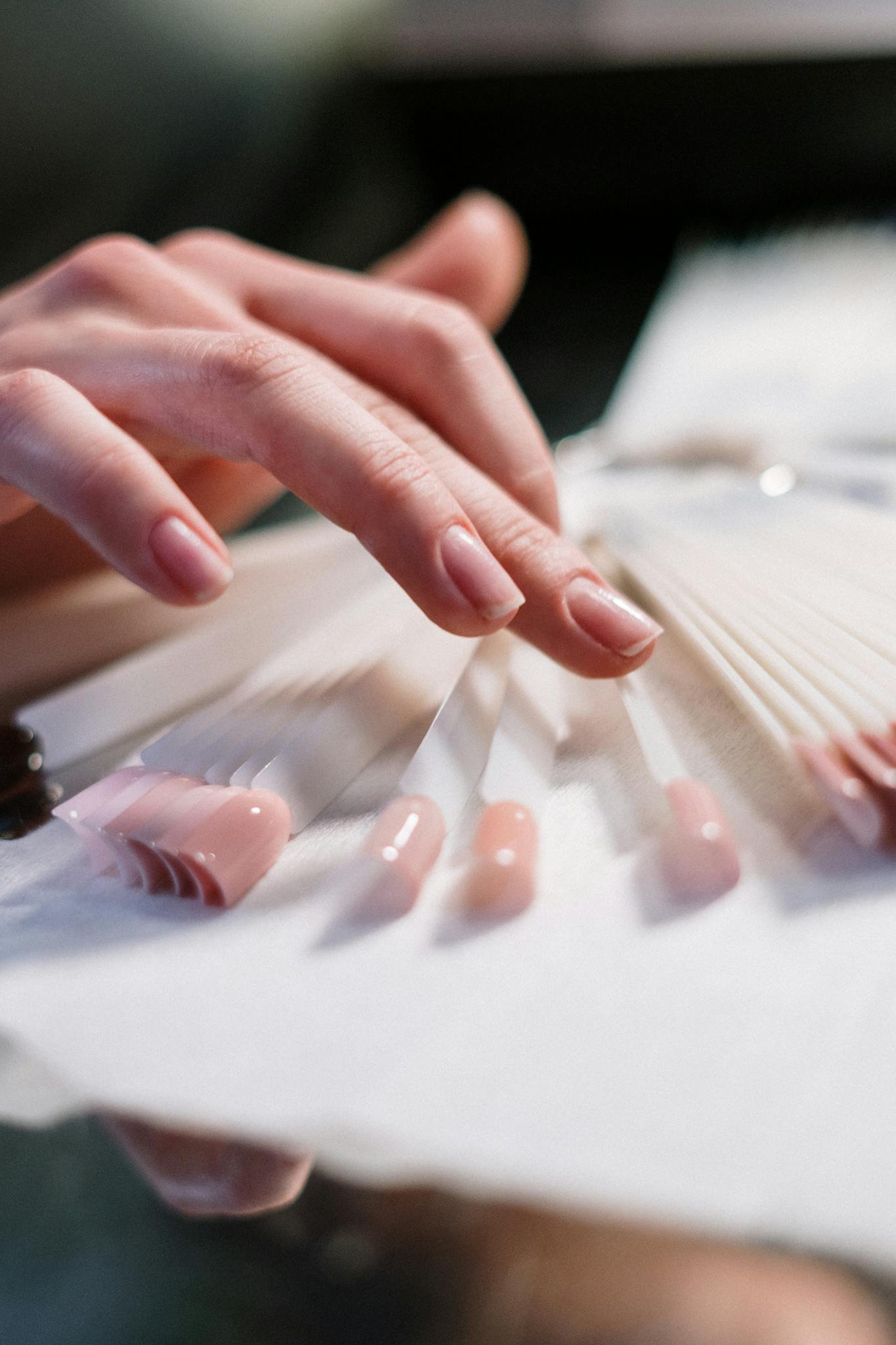 Close-up of a woman's hand selecting nail polish colors in a beauty salon.